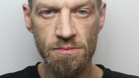 A man with a beard and wearing a black t-shirt.