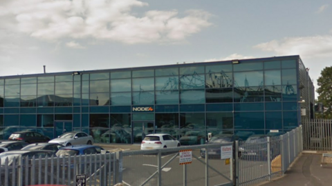 A blue glass building in an industrial park