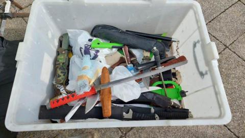 A white box full of knives that have been handed in by members of the public