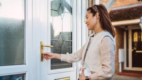 Young woman opening front door with key