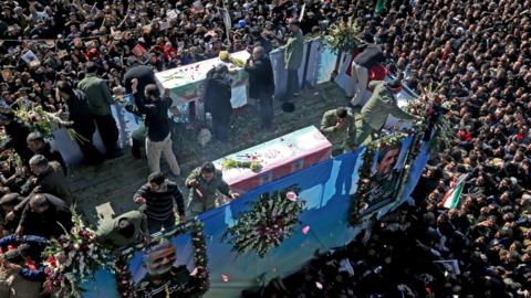 Iranian mourners gather around the funeral procession for General Qassem Soleimani