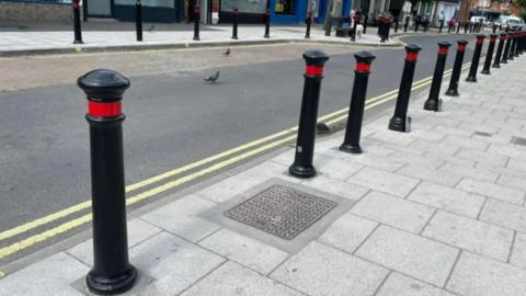 Black and red bollards placed along pavement in a street in York