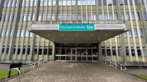 The entrance to a library building. A sign over the doors says "City Central Library".