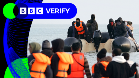Migrants wading through water to get on a small boat