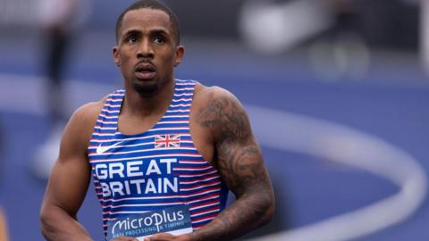 Ujah looking away from the camera with a slightly concerned look, wearing his a Great Britain blue competition tank top