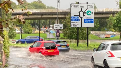 Cars driving through flood water near a roundabout