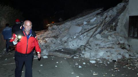 People walk past rubble as rescue operations begin in Villa Sant'Antonio village, near Visso, Marche region, Italy, on 26 October 2016