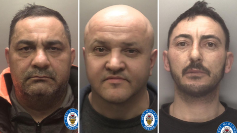Three men pictured in mug shots. Aldafin Poenaru has short black hair, dark stubble around his mouth ad wears a black and orange hood jacket. Sorin Condrache is bald and wears grey shirt, while Marian Agarlita has spikey black hair, a black moustache and black beard. He is wearing a black tshirt.
