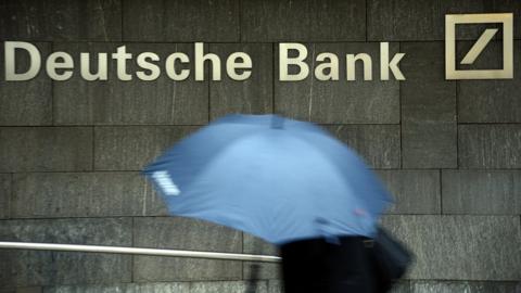 A woman with a umbrella passes a logo of Deutsche Bank on January 29, 2013 in Frankfurt am Main, Germany