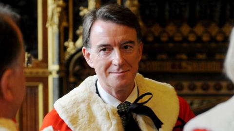 Peter Mandelson smiles while speaking to others during his induction into the House of Lords in 2008 - he wears traditional lords robes.