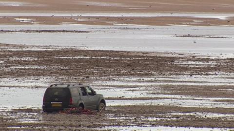 The stranded car buried up to its wheels in sand on Cleethorpes beach.