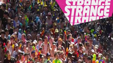 A crowd in a water fight and the Strange logo