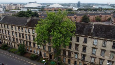 Row of Glasgow tenements from above with Argyll Ash in the middle and a panoramic view of Glasgow in the background