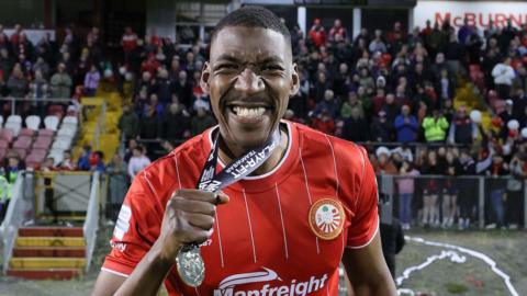 A man in a red and white striped football top celebrating with a medal around his neck