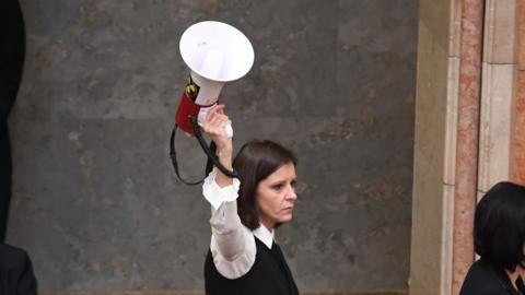 Member of Parliament Bernadett Szel (C) holds a siren-horn in parliament, 12 December 2018