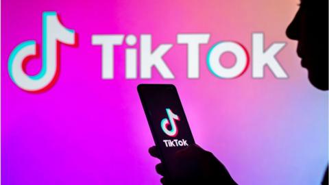 Person's silhouette in front of TikTok logo