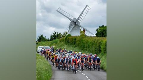 Ride London cyclists riding along a country road, with the backdrop of a white windmill