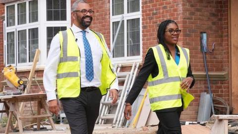 Sir James Cleverly and Kemi Badenoch visit a building site, dressed in high vis jackets