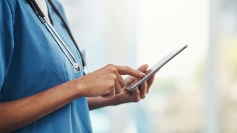 A woman nurse looking at a tablet computer