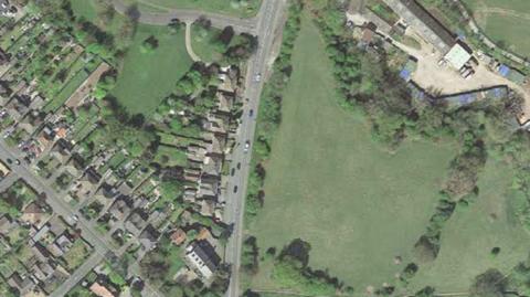 An aerial view of houses, roads and green space