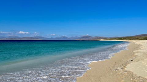 A photo of a deserted beach beneath sunny skies