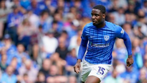 Christian Saydee in action for Portsmouth FC. He is wearing a blue football shirt and white shorts. 