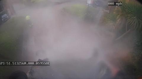 Image from CCTV footage showing smoke surrounding upside down bin 