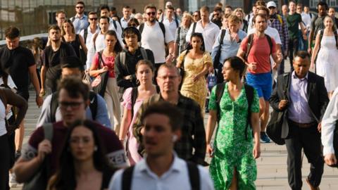 Commuters cross London Bridge on their way to work at the City of London, UK, on Monday, Aug. 12, 2024