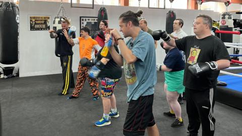 A group of people punching the air and some are wearing boxing gloves