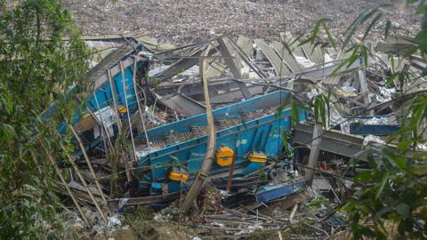 The remnants of a destroyed structure, including bent metal pieces, lie at a landfill site in Cebu surrounded by rubbish.