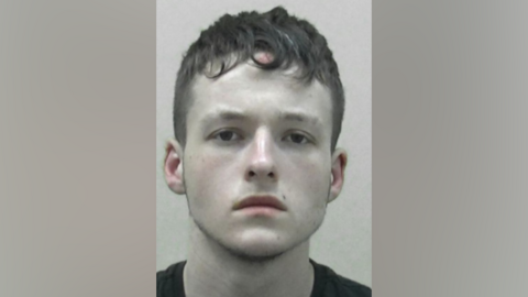 A police custody image of Jordan Tams, who is a young man with short brown hair.