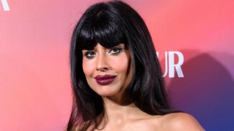 Broadcaster and activist Jameela Jamil, a woman with long dark hair and red lipstick looks into the camera