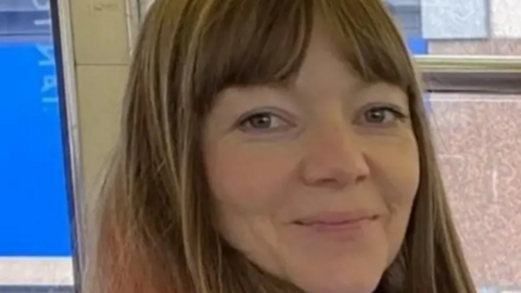 Joanne Samak, a woman with long light brown hair, smiles at the camera.