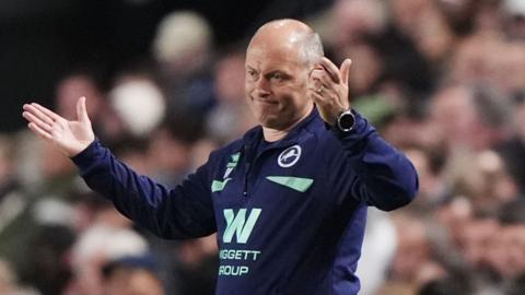 Alex Neil raises both his hands in the air level with his shoulders and shrugs with an annoyed expression on his face