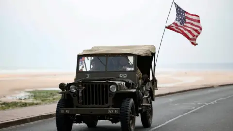 World War II reenactors drive a Willys Jeep ahead of the 80th anniversary of the 1944 D-Day landings in Vierville-sur-Mer above Omaha Beach, Normandy region, France, June 1, 2024.
