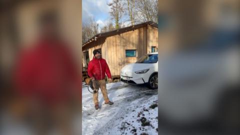 man standing outside his eco cabin in the snow 
