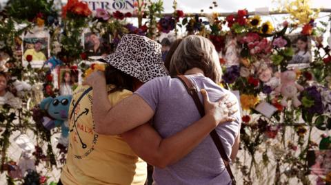 Two women mourn at a memorial for the victims of the Texas floods