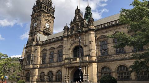 Sheffield town hall is a gothic style Victorian building made from stone with a clock tower, large arched windows and steps leading to a grand entrance