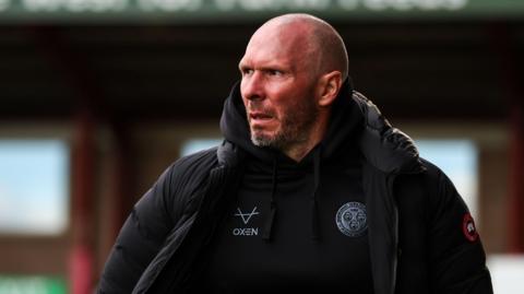 Michael Appleton walks along the touchline in his Shrewsbury Town puffer coat