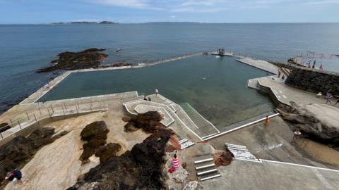 A wide picture taken taken above La Vallette bathing pools with the sea and the smaller islands in the background