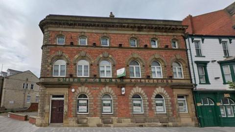 The building that previously housed Smith and Graham solicitors office. The three storey red-brick building has decorative arches around the windows and doors.
