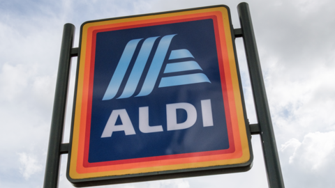 The Aldi logo, which includes a light blue design on a darker blue background. The sky is prominent in the background behind the sign.