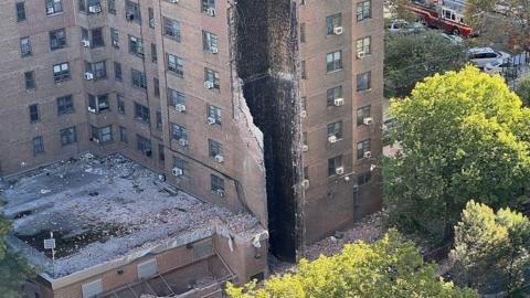 Picture showing partially collapsed building in New York - the "scar" is top to bottom and shows a centilation shaft attached to the building totally destroyed, with piles of red brick rubble on the floor