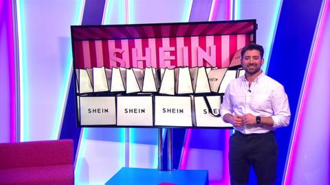 ricky smiling next to a tv plasma showing an image of shein shopping bags piled high