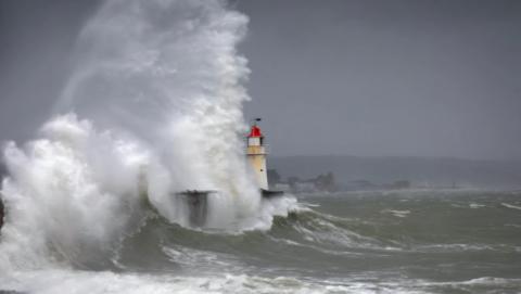 Waves smash against a lighthouse in Newlyn in Cornwall