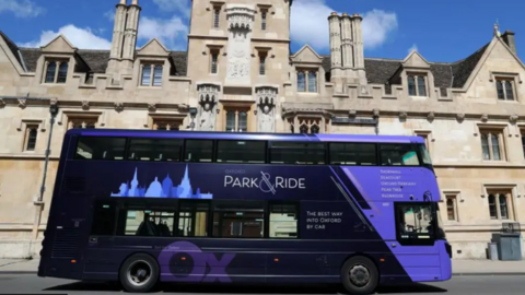 A purple Park & Ride bus drives along an Oxford street.