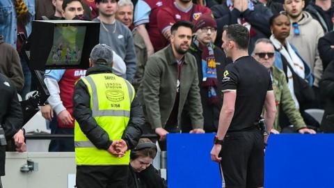 Match referee Chris Kavanagh reviews a VAR decision on a West Ham goal during the Premier League match between West Ham United and Arsenal at the London Stadium 