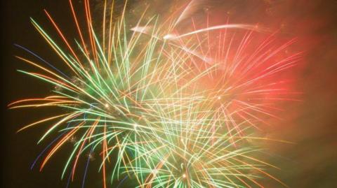 A fireworks display showing several exploding fireworks, in green and red, against a dark sky