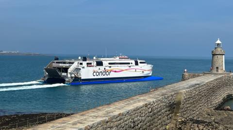 The Condor Voyager leaving St Peter Port harbour with a lighthouse to the right of the picture.