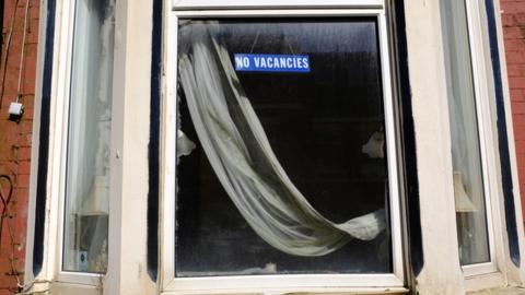 A run down b&b window with a no vacancy sign